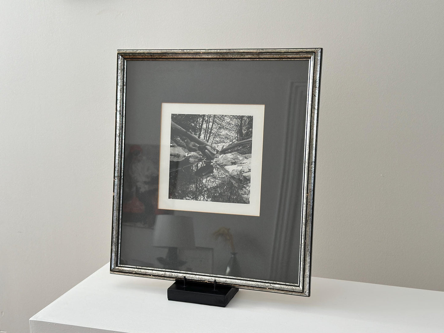 Vintage black and white photograph of a woman crouching in a brook in a vintage frame