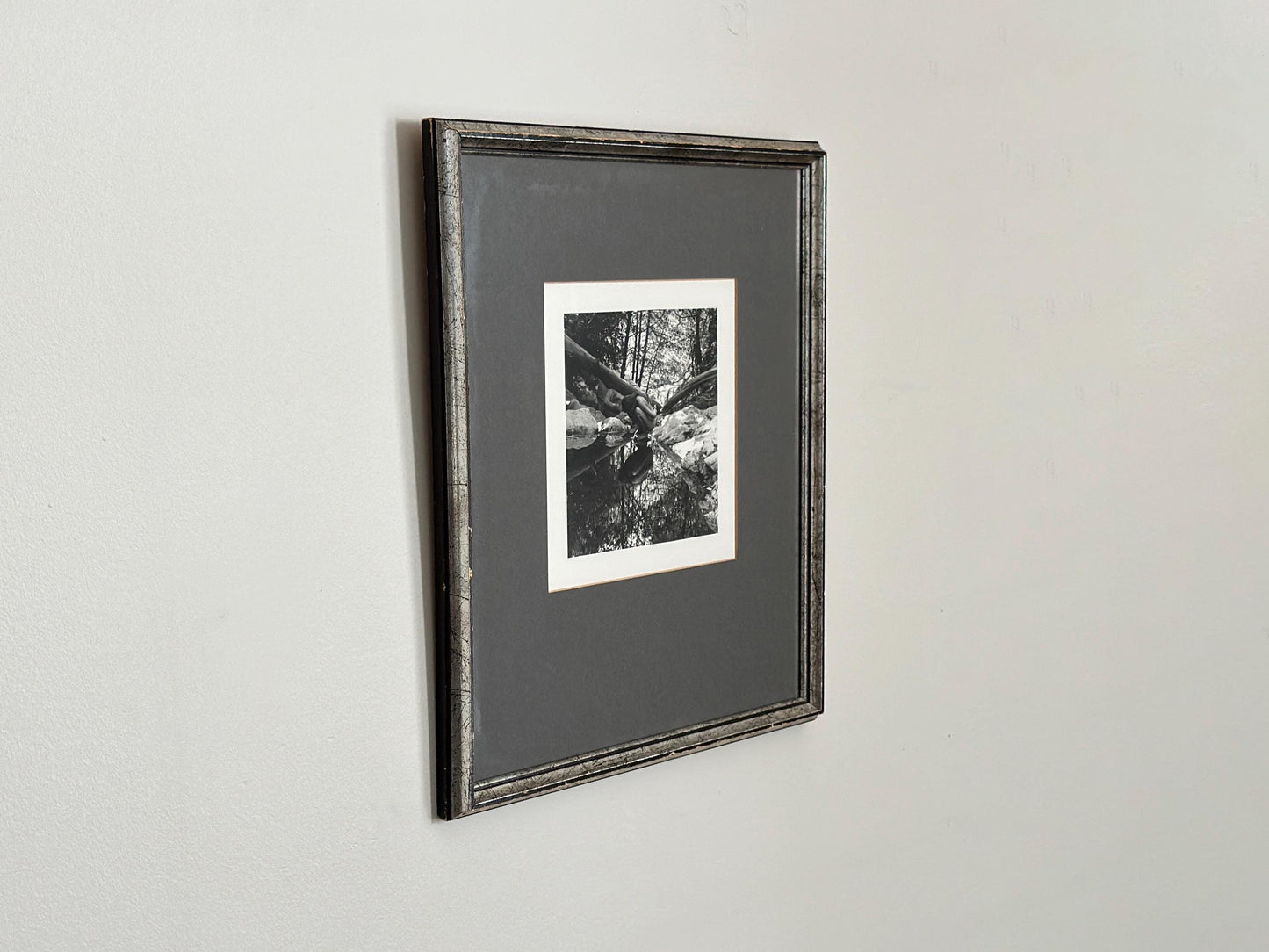 Vintage black and white photograph of a woman crouching in a brook in a vintage frame