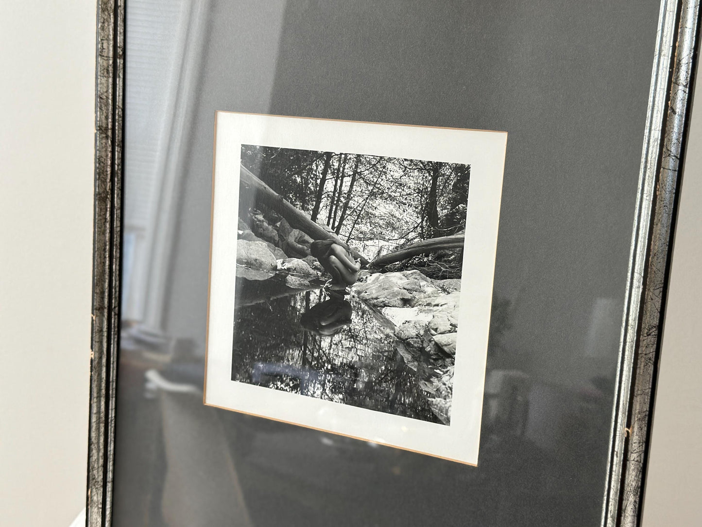 Vintage black and white photograph of a woman crouching in a brook in a vintage frame